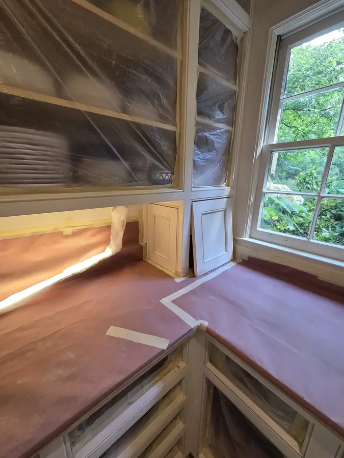 Kitchen cabinet painting preparation with countertops carefully masked