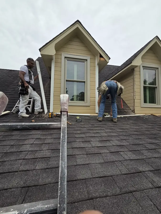 Painting crew replacing trim around an exterior dormer window