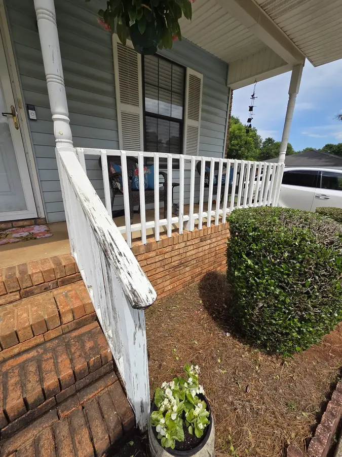 Finished white porch railing after replacement and painting